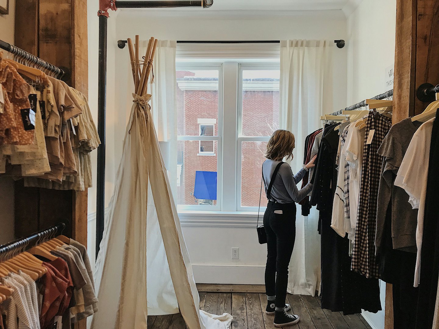 Woman browsing clothes on a rack in a boutique.