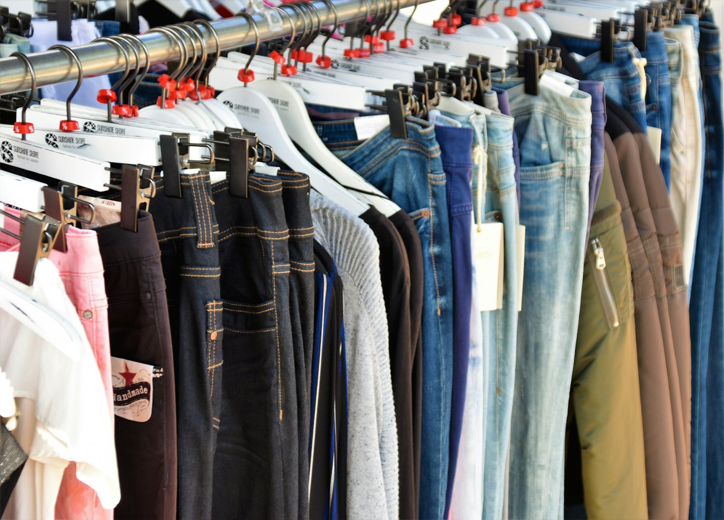 Clothing rack with various pants and tops for sale.